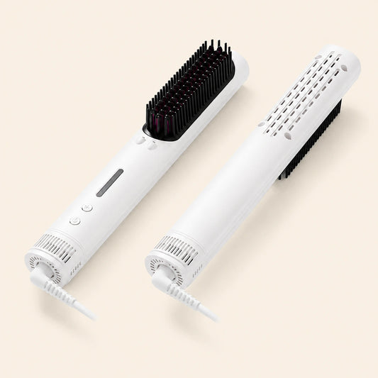 Two white electric hairbrushes shown on a light beige background, one upright and one angled to show the brush head and vented body.