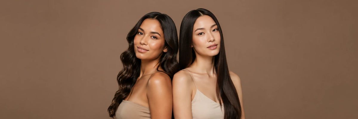 Two women with shiny wavy black hair and sleek straight black hair pose together against a warm brown background.